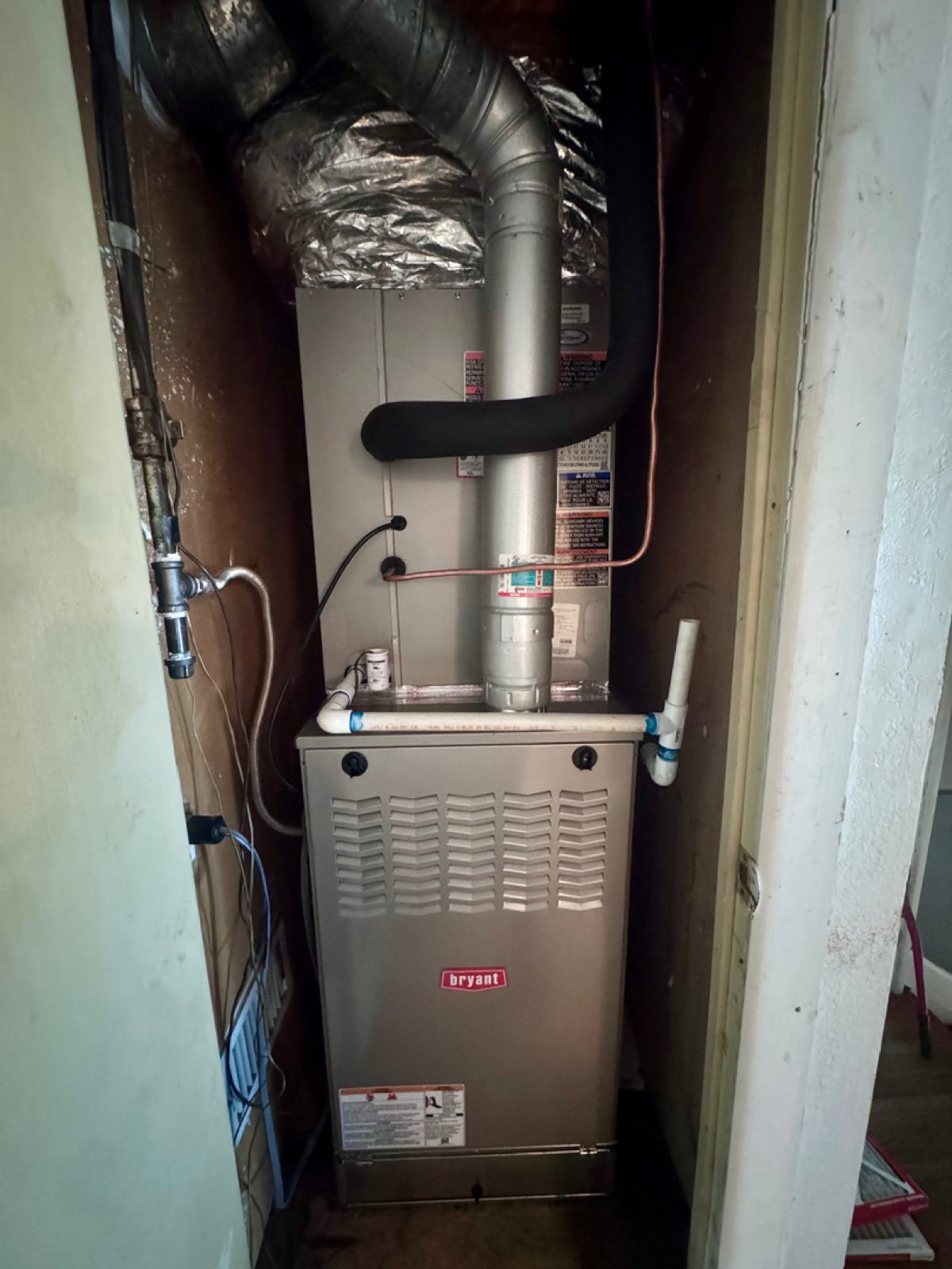 Bryant furnace installed in a home utility closet with flex ductwork and PVC drain lines by Wright Choice in Abilene, TX