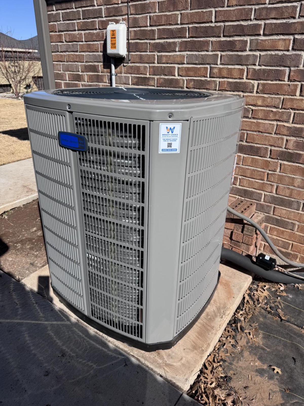 American Standard AC condenser with a Wright Choice service sticker installed against brick in Abilene, TX